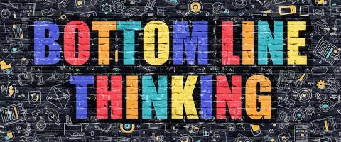 "Bottom Line Thinking" in graffiti-like writing on black wall
