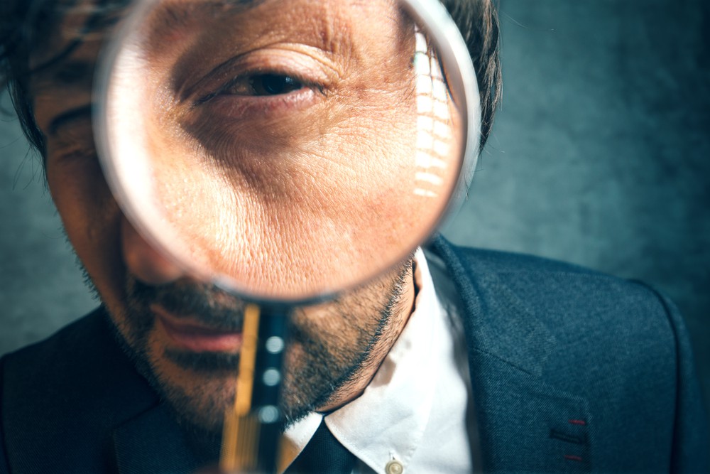 Professional looking through a magnifying glass representing picking an IT partner