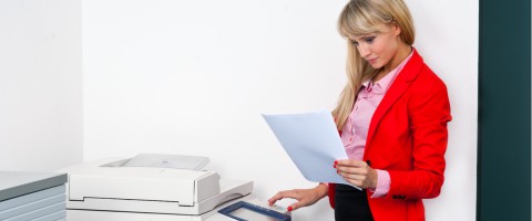 Businesswoman reviewing a printed document at a copier