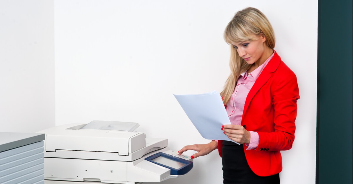 Businesswoman reviewing a printed document at a copier