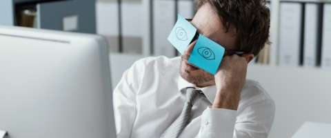 Concept of neglecting system updates. Man behind a computer with his eyes covered by sticky notes.
