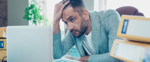 Exhausted IT worker behind a laptop representing IT burnout
