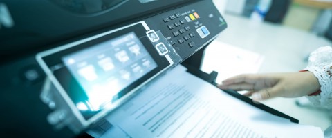 Close up of a multifunction printer's interface and documents on the output tray