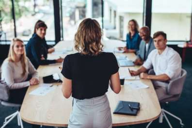 Team of employees sits around a table discussing the benefits of Managed Print Services. 