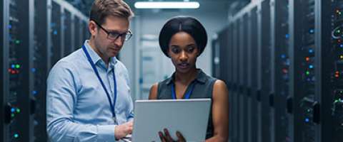 Two IT workers standing in a massive server room