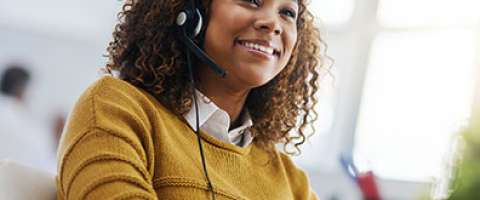 Smiling african american woman IT worker with headset talking over VoIP
